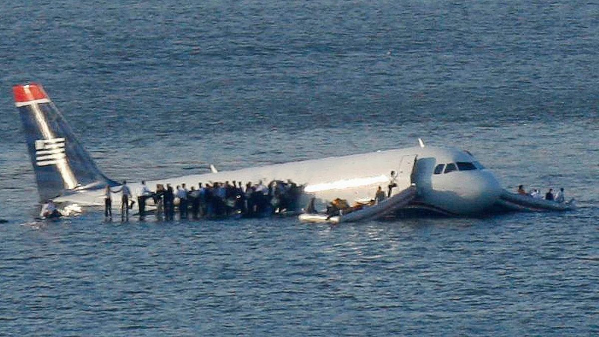 Plane in the Hudson River with passengers standing on the wings
