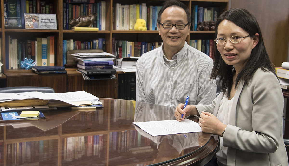 Dr. Liwei Zhang, right, and AE chair Dr. Vigor Yang, sitting at a table with their research papers before them