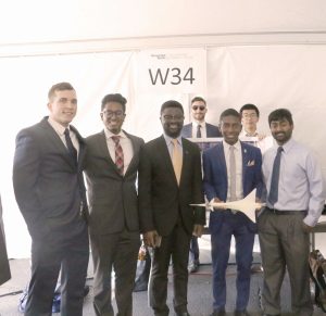 Members of Team MACH-ingjay pose with a model of their vehicle design