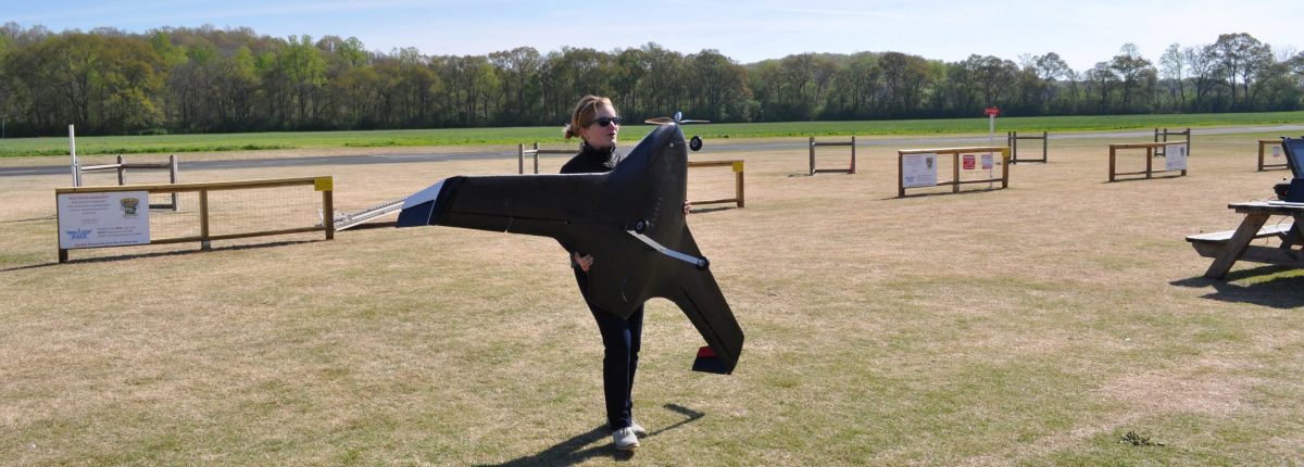 An aerospace engineering student holding a very large plane prototype during the 2014 AerosPACE competition