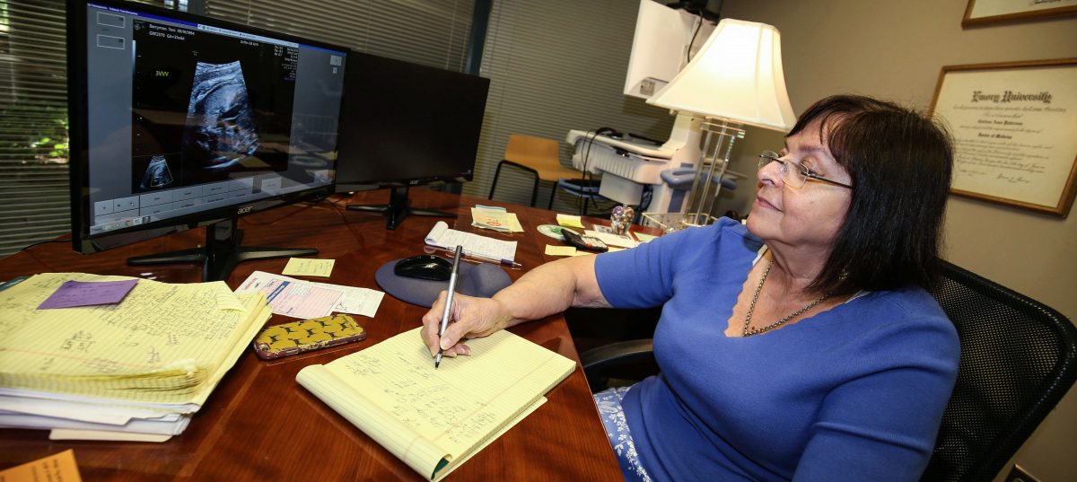 Anne Patterson in her medical office, looking at a sonogram on the computer screen in front of her