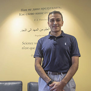 Nelson Guecha standing in front of some quotes on a wall  in the Modern Language building