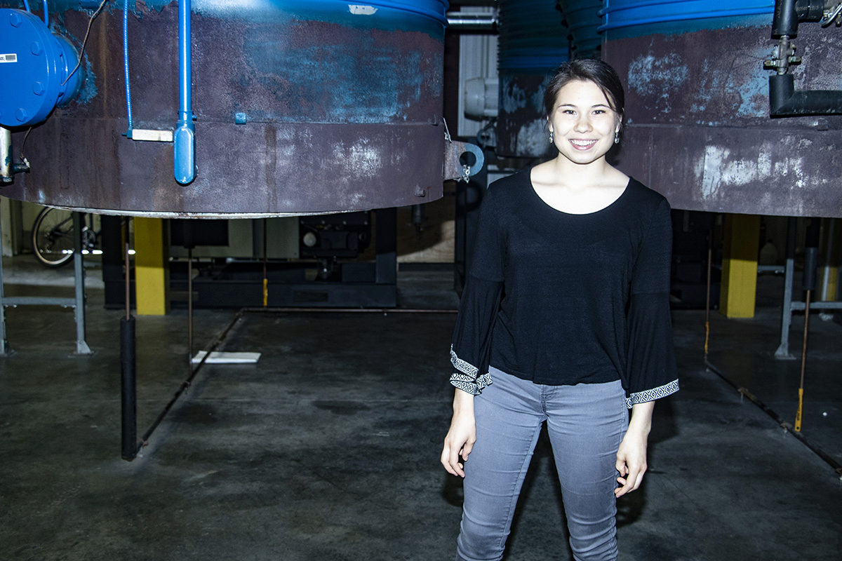 Abigail McClain standing in front of one of the vacuum chambers at the HPEPL