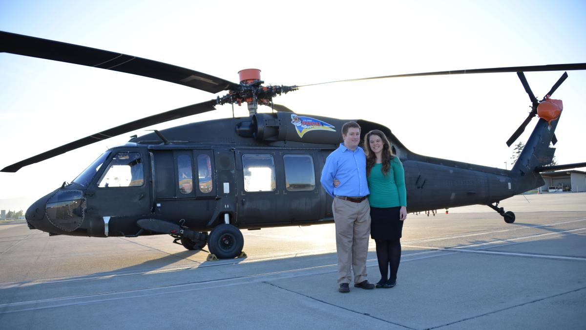 Natasha poses in front of a helicopter with her husband David Schatzman